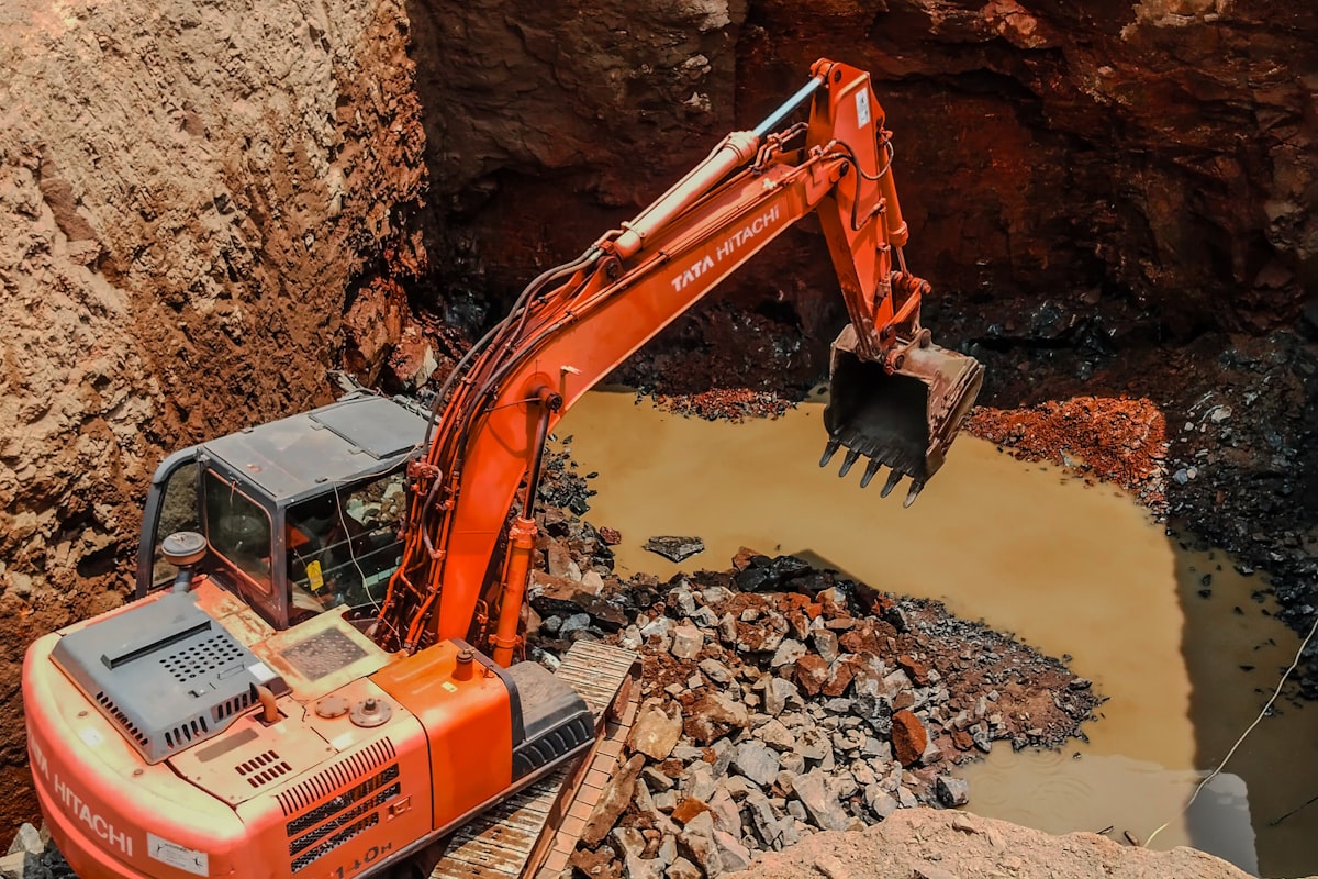 An excavator digging in a muddy pit